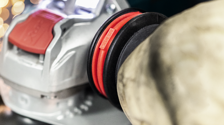 Električno orodje, priključeno na veliko fleksibilno cev za odsesavanje prahu.